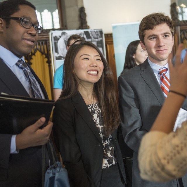 Three students speak with a recruiter around a table during a career fair.