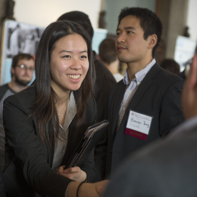 A student shakes hands with someone at a career fair.