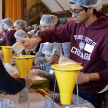 A student helps pack meals at a volunteer event. 