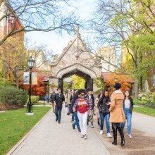 A tour guide takes a group of people around a college campus.