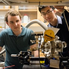 Two students post with their levitation experiment inside a physics lab.