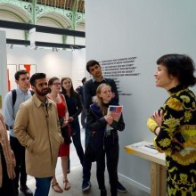 A group of students in Paris converse with a staff member in an art museum.