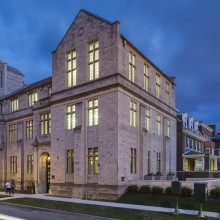 A street photo of the outside of the Neubauer Collegium building at dusk.
