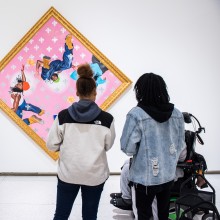 A group of five students view a brightly colored piece of art that is hanging sideways on a wall in a museum.