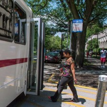 A person steps aboard a campus shuttle bus in summer.