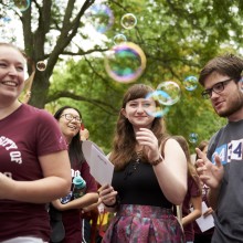 Students blow bubbles at convocation. 