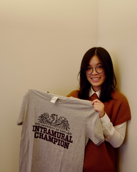 A student stands holding a tshirt that reads "Intramural Champion"