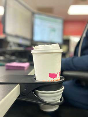A staff member at Jordana's high school uses the initial prototype of the Sip 'N Clip at her desk to prevent spills.