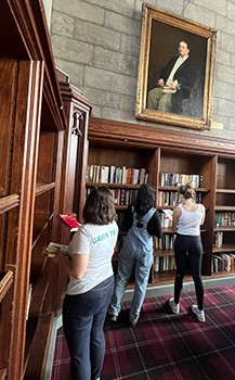 Three students add books to the shelves in Harper Memorial Library