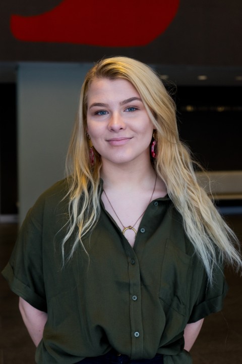 A female student poses for a headshot in front of a colorful background.