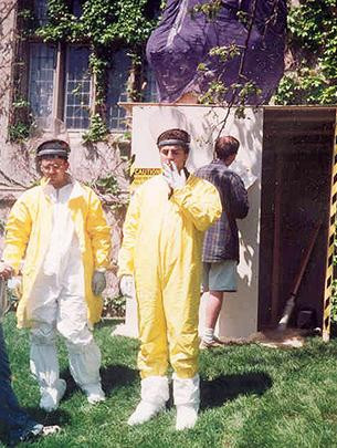 Two men stand outside in yellow jumpsuits in front of a man-made nuclear reactor on UChicago's campus.