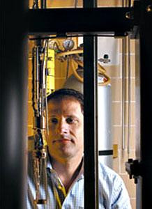 Thomas Rosenbaum stands near equipment in lab like environment.
