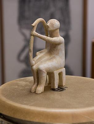 A small stone sculpture of an harpist sits atop a drum.