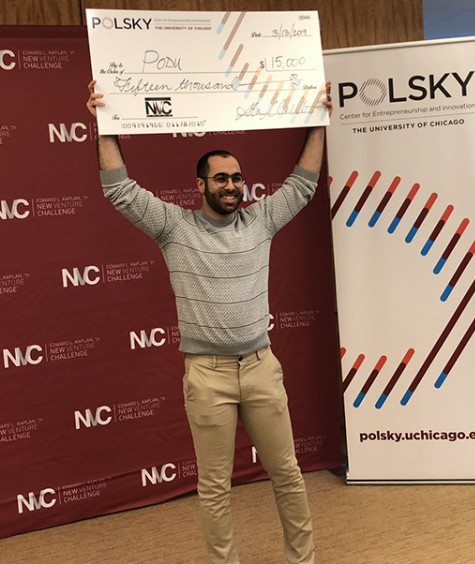 A student holds a giant check in front of a poster that says "New Venture Challenge" and beside a banner that says Polsky Center for Entrepreneurship and Innovation.