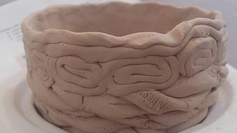 A close up shot of a white clay bowl before it is fired. The bowl is made with coiling pieces of clay. of
