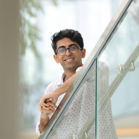 A portrait of Vivek Ramakrishnan on a set of stairs with a glass railing.