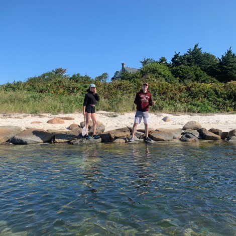 Two students work with a net by the water