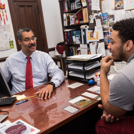 Adviser Shawn Hawk talks with a student at the desk in his office.