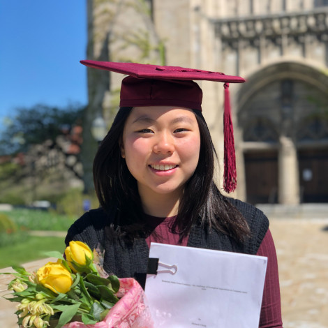 A portrait of Michelle Chong in cap and gown outside Rockefeller chapel.